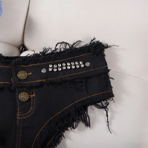 Dettaglio di pantaloncini di jeans neri con strass argentati e bordi con frange