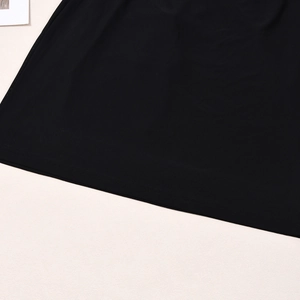 Detailed view of the black dress hemline featuring professional stitching and fabric texture