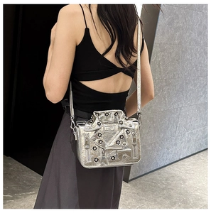 Detail of silver metallic jacket-shaped crossbody bag with black floral rivets on a model