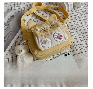 Detail of yellow canvas crossbody bag with 3D bear ears and cute cartoon badges