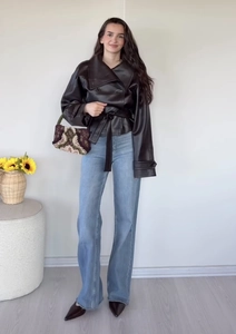 Gesamtansicht der schwarzen zweireihigen PU-Lederjacke mit Gürtel und Denim-Hose