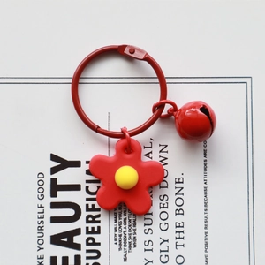 Cute red knit flower keychain with small bell and yellow center on decorative card