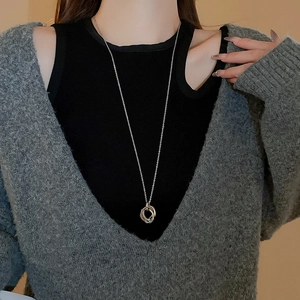 Detail shot of a minimalist silver interlocking triple-ring pendant necklace on a model