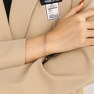 Macro detail of minimalist silver open cuff bracelet with bead ends on female wrist