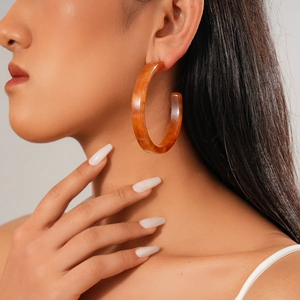 Macro shot of large amber acrylic round earrings with vintage tortoiseshell resin texture
