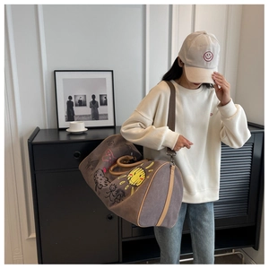 Lifestyle shot of large canvas duffel bag with hand-drawn graffiti and shoulder strap