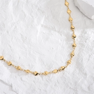 Minimalist gold heart chain necklace elegantly displayed on white textured stone background