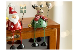 Detailed view of hand-painted metal Santa and Reindeer ornaments with hanging legs on wood