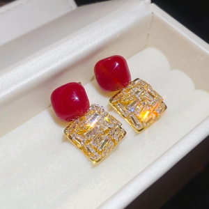 Détail de boucles d'oreilles vintage en zircon rouge dans un coffret en velours blanc