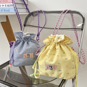 Detail of drawstring bucket bags with checkered pattern and cute cow embroidery patch