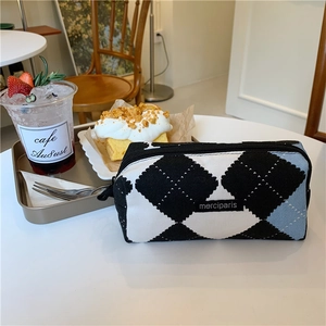 Close-up of knit checkered makeup pouch on a cafe table with soft morning lighting