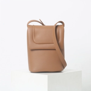 Vue détaillée du sac à bandoulière en cuir souple marron sur un support blanc minimaliste