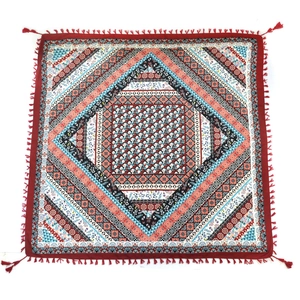 Close-up of bohemian square scarf with red geometric patterns and knotted fringe detail