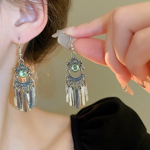 Detailed shot of ethnic phoenix moon earrings with silver fringe and green beads