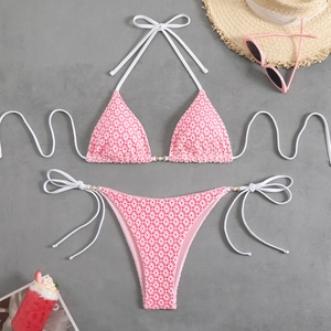 Detailed flat lay of pink abstract geometric bikini set with beach vacation accessories