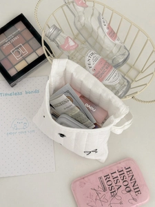 Quilted white sanitary napkin storage bag with black bow and cosmetic organization items