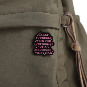 Enamel pin on military green backpack with motivational text for daily accessory