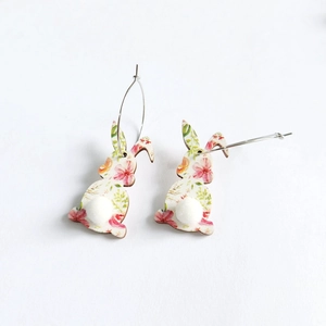 Detail of floral Easter bunny earrings with white fuzzy pom-pom tails on white background