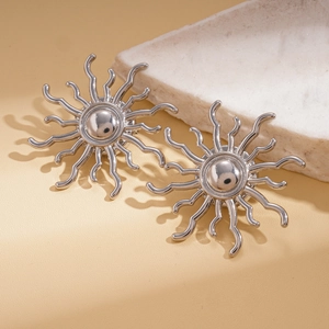 Macro shot of silver sunburst earrings with metallic wavy radial design on stone base