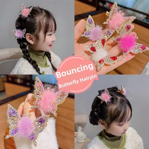 Close-up of animated butterfly hair clips with sparkling rhinestones and plush pom-poms
