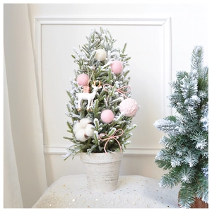 Detail of mini flocked Christmas tree with pink pom poms and small reindeer ornament