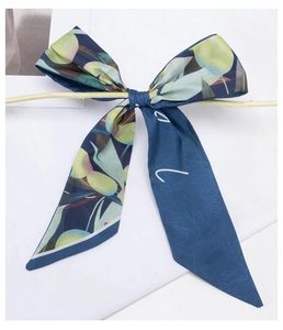 Close-up of dark blue silk scarf with floral patterns tied on a branch in minimalist style