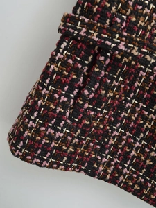 Macro view of textured tweed fabric with black, pink, and gold metallic thread weave