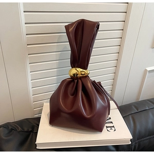 Detail of wine red drawstring bucket bag with long pleated handle and gold pebble ring