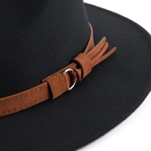Close-up of brown leather band with gold ring and fringe on a black wool fedora hat