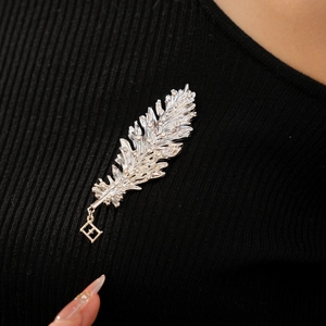 Detailed view of a silver leaf brooch with shimmering crystals on black knit fabric
