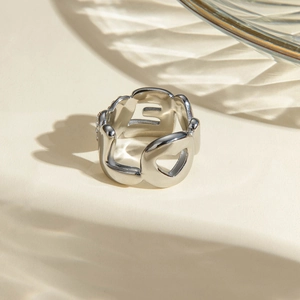 Gros plan d'une bague argentée avec lettres découpées et détails scintillants élégants