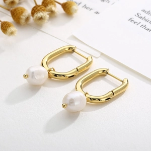 Vintage gold U-shaped hoop earrings with elegant pearl drop on a minimalist background