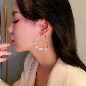 Gros plan d'un mannequin portant de grandes boucles d'oreilles cœur argentées avec cristaux