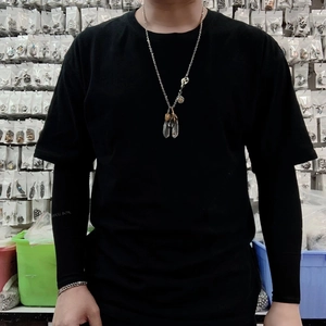 Detail of vintage feather pendant necklace worn by model in a stylish hip hop aesthetic