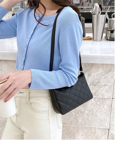 Detail of black quilted underarm bag with elegant diamond stitching and shoulder strap