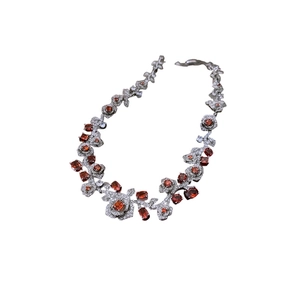 Vintage style necklace featuring silver rose motifs and vibrant orange-red zircon stones