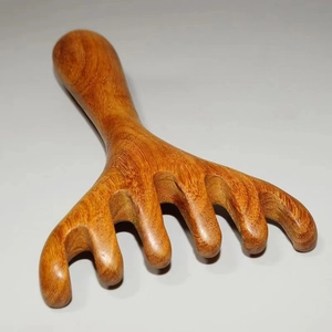 Macro shot of sandalwood scalp massage comb with five rounded teeth and natural wood grain