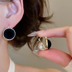 Detailed shot of black flocked earrings with white pearls and gold metal clasps