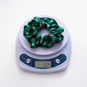 Close-up of a green plaid Christmas scrunchie with snowflake pattern on a digital scale