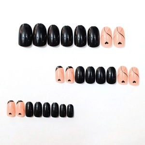 Elegant black and nude pink oval press-on nails with heart patterns and gold glitter