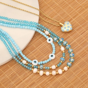 Close-up of pearl and evil eye beaded necklace with heart-shaped enamel pendant detail