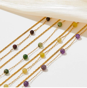 Close-up of golden stainless steel bracelets with colorful natural stone beads on silk