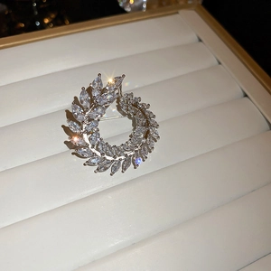 Macro shot of silver leaf wreath brooch with white zircons in a white jewelry box