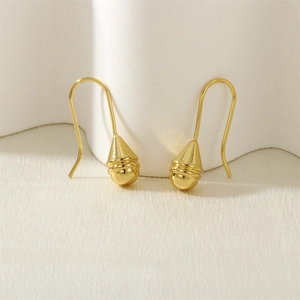 Macro detail of golden teardrop earrings with textured stripes and U-shaped hooks
