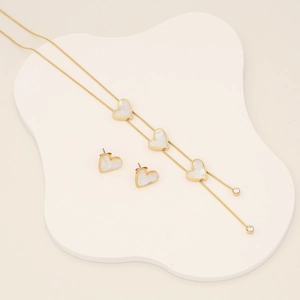 Golden heart jewelry set with white shell inlay, necklace and earrings on white tray