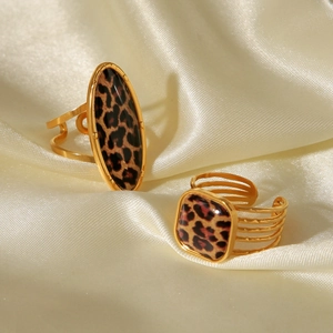 Detailed view of two gold leopard print rings on elegant cream silk fabric texture