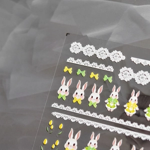 Detail view of 3D embossed nail stickers with cute white rabbits and floral patterns