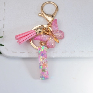 Close-up of pink glitter butterfly keychain with resin letter pendant and tassel