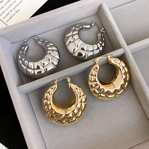 Detailed macro view showing gold and silver textured hoop earrings on a velvet tray