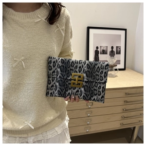 Detail view of leopard print clutch featuring a luxury gold buckle and soft plush texture